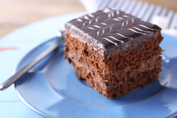 Sweet chocolate cake on blue plate on wooden table, close up