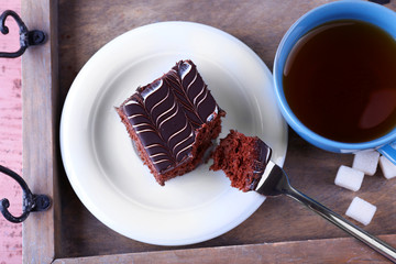 Served table with a cup of tea and chocolate cake on wooden background close-up