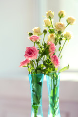 Beautiful spring flowers in vase on window background