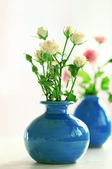 Beautiful roses in turquoise vases on window background