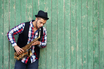 The musician plays saxophone on green wooden background