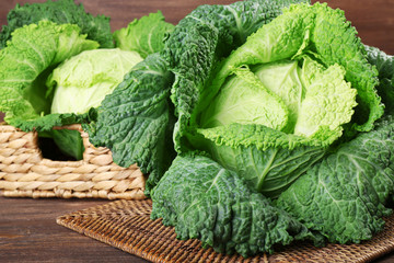 Savoy cabbage in wicker basket on wooden background