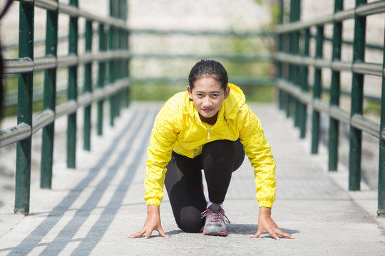Young asian woman exercising outdoor in yellow neon jacket, gett