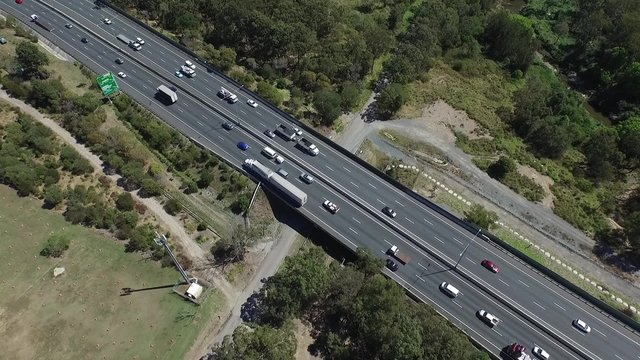Elevated aerial view of freight semi trailer lori trucks, vehicles and cars traveling on high speed freeway or motorway driving scenes on open road on Gateway Motorway Australia.