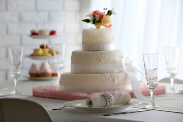 Fototapeta na wymiar Wedding layered cake on decorated table in restaurant