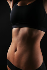 Fototapeta premium Slim female body in nice black lingerie on dark background