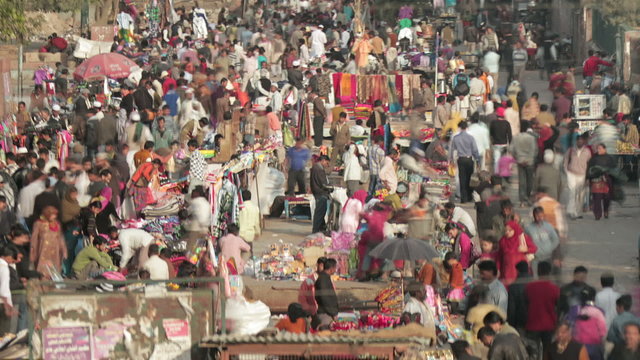 Time-lapse of crowds in street market in Delhi, India. Camera pans right to left