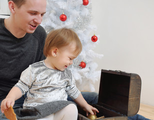 cute little baby girl and her dady having fun with Christmas toy