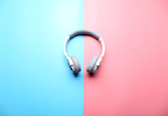 Wireless white and grey headphones on pink-blue background