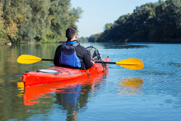 The man is kayaking on the river.