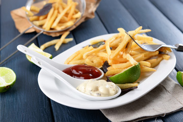 French fried potatoes with sauce and lime on white tray