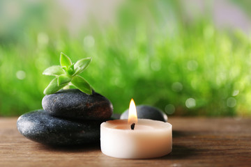 Spa stones and candle on wooden table closeup