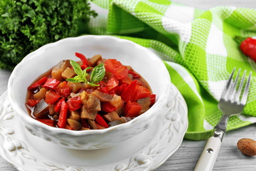 Ratatouille in bowl, on wooden table background