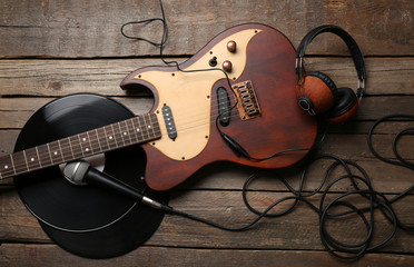 Naklejka premium Electric guitar and headphones with microphone and vinyl on wooden background