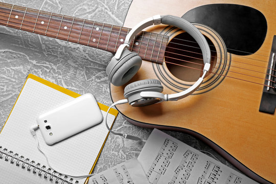 Classical guitar and headphones with phone on grey background