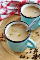Mugs of soup on wooden mat closeup