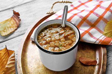 Mug of soup on metal tray on a table
