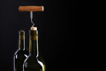 Corkscrew and wine bottle on a black background
