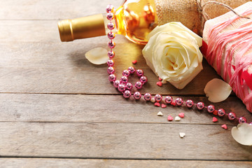 Setting of a bottle of wine, a gift in the box and other decoration, on wooden background