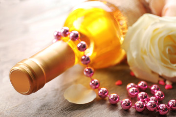 A bottle of wine, bead and a white rose on wooden background, close-up