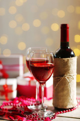 Setting of a bottle of wine, gifts in the boxes and other decoration, on blurred background
