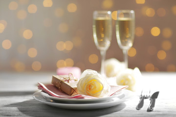 Glasses of wine and white roses, on blurred background