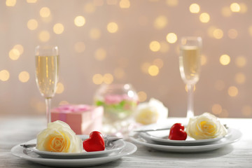 Glasses of wine and white roses, on blurred background