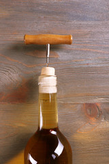 Corkscrew and wine bottle on wooden background