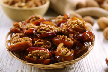 Walnut and date fruit in plate on wooden table, close-up