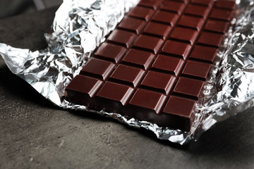 Fototapeta na wymiar Chocolate bar in foil on gray background
