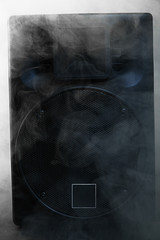 Black loudspeaker in a smoke on dark background