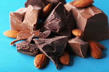 Black chocolate pieces with nuts on color wooden background