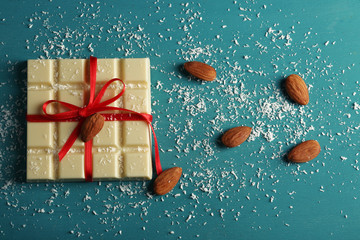White chocolate bar with coconut shavings on color wooden background