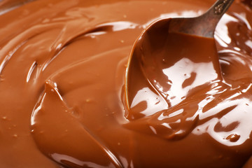 Background of melted milk chocolate and a spoon, close-up