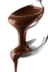Melted milk chocolate pouring from spoons, isolated on white, close-up