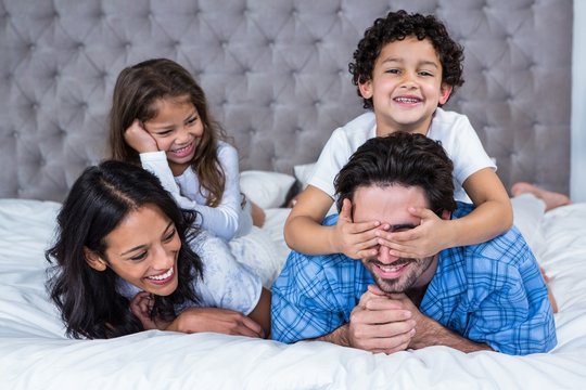 Smiling Family Laying On The Bed