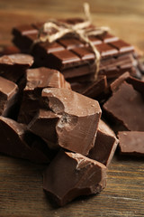 Chocolate pieces, shavings and cocoa beans on color wooden background