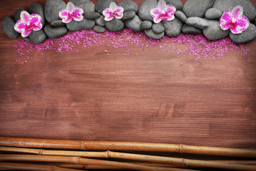 Spa stones and orchids on wooden background