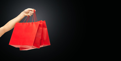 close up of hand holding red shopping bags