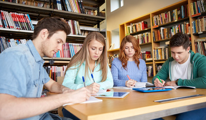 happy students writing to notebooks in library