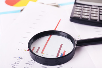 A magnifying glass on financial documents background, close-up