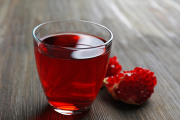 A glass of tasty juice and garnet fruit, on wooden background