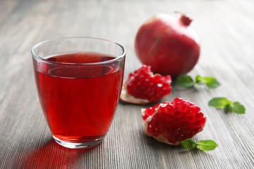 A glass of tasty juice and garnet fruit, on wooden background