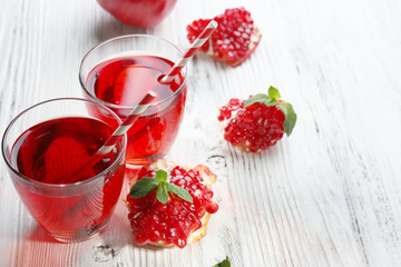 Two glasses of tasty juice and garnet fruit, on wooden background