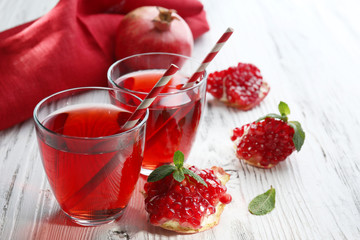 Two glasses of tasty juice and garnet fruit, on wooden background