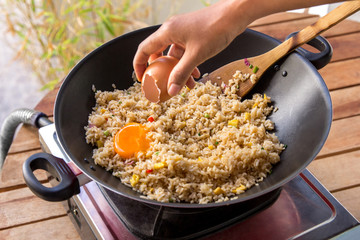 human hands adding egg into fried rice