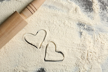 Hearts of flour and rolling pin on gray background