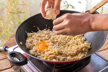 human hands adding egg into fried rice