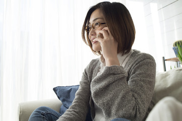 Women are talking in smart phone sitting on the sofa