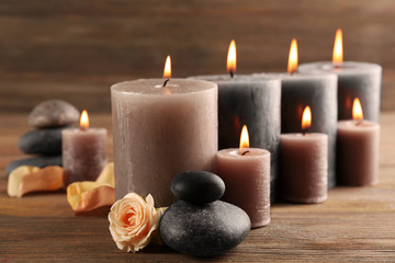 Fototapeta na wymiar Alight wax grey candles with roses on wooden background